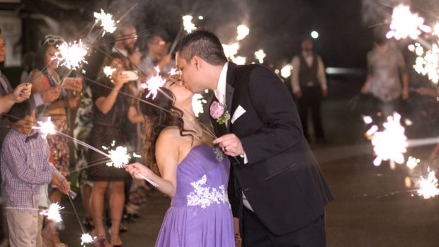 Sparklers burn as a bride and groom exit their wedding reception in Dallas, tx