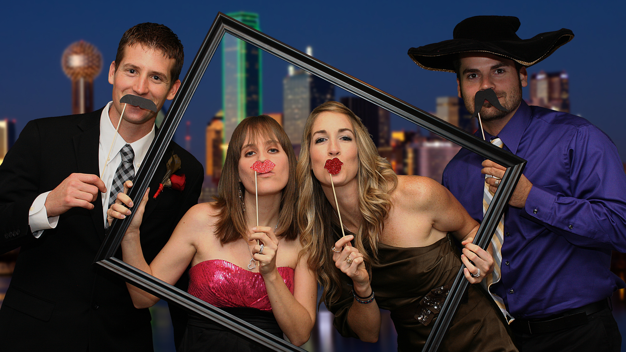 Friends pose for photography at a wedding in a digital sharing photosation. They are seen inside a picture frame with a green screen image of Dallas in the background.