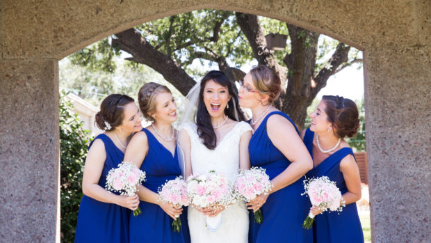 Bride, Milena, poses with her bridesmaids for wedding photographer at the bell tower chapel in Fort Worth, TX
